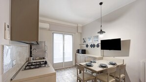Une cuisine compacte équipée d’une cuisinière à gaz, d’un four à micro-ondes et d’une table à manger avec des chaises.