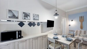 Une cuisine moderne équipée d’un four à micro-ondes, d’une table à manger, de chaises et d’un téléviseur à écran plat.