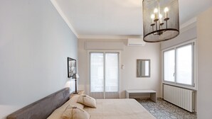 Une chambre à coucher avec un lit, une table de chevet, une lampe et une grande fenêtre.