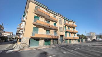 Un immeuble résidentiel à plusieurs étages, doté de balcons, d’un garage et surplombant un ciel dégagé.