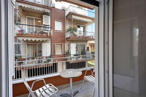 Ein Balkon mit Tisch und Stühlen, Blick auf benachbarte Gebäude und eine Tür zum Innenbereich.
