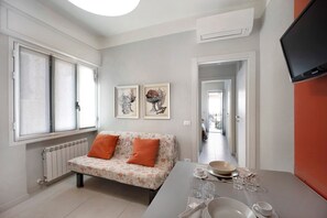 Un salon moderne avec un canapé, une table à manger dressée et des œuvres d’art accrochées au mur.