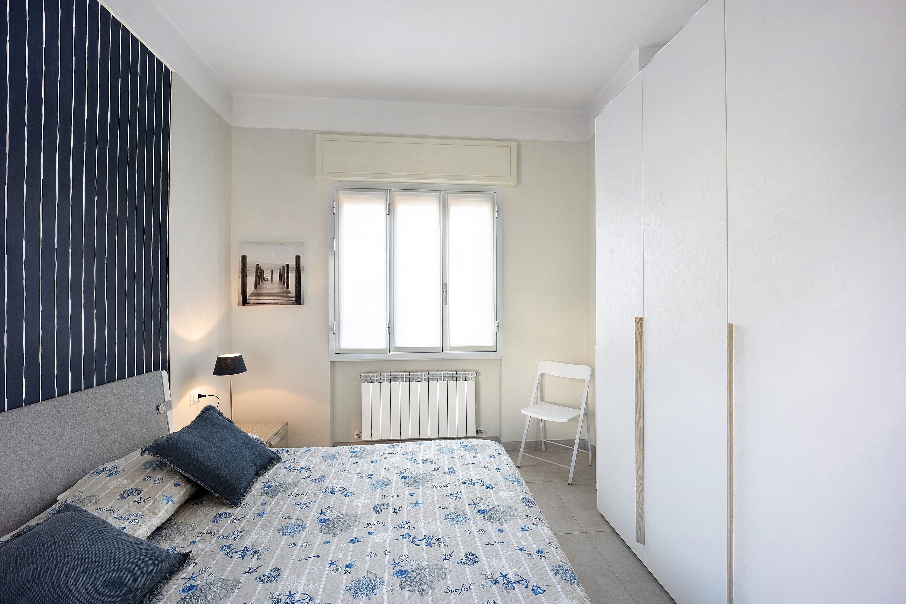 Une chambre à coucher avec un lit, une chaise, un radiateur et une fenêtre.