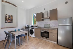 A compact kitchen with a washing machine, oven, and a refrigerator.