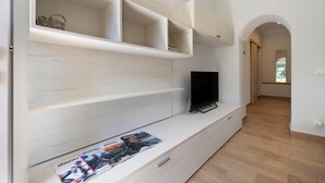 A modern living room with built-in shelves, a flat-screen TV, and a magazine on the floor. - Ca di perti Apartment 1 with Wi-Fi, A/C & Garden (Finale Ligure)