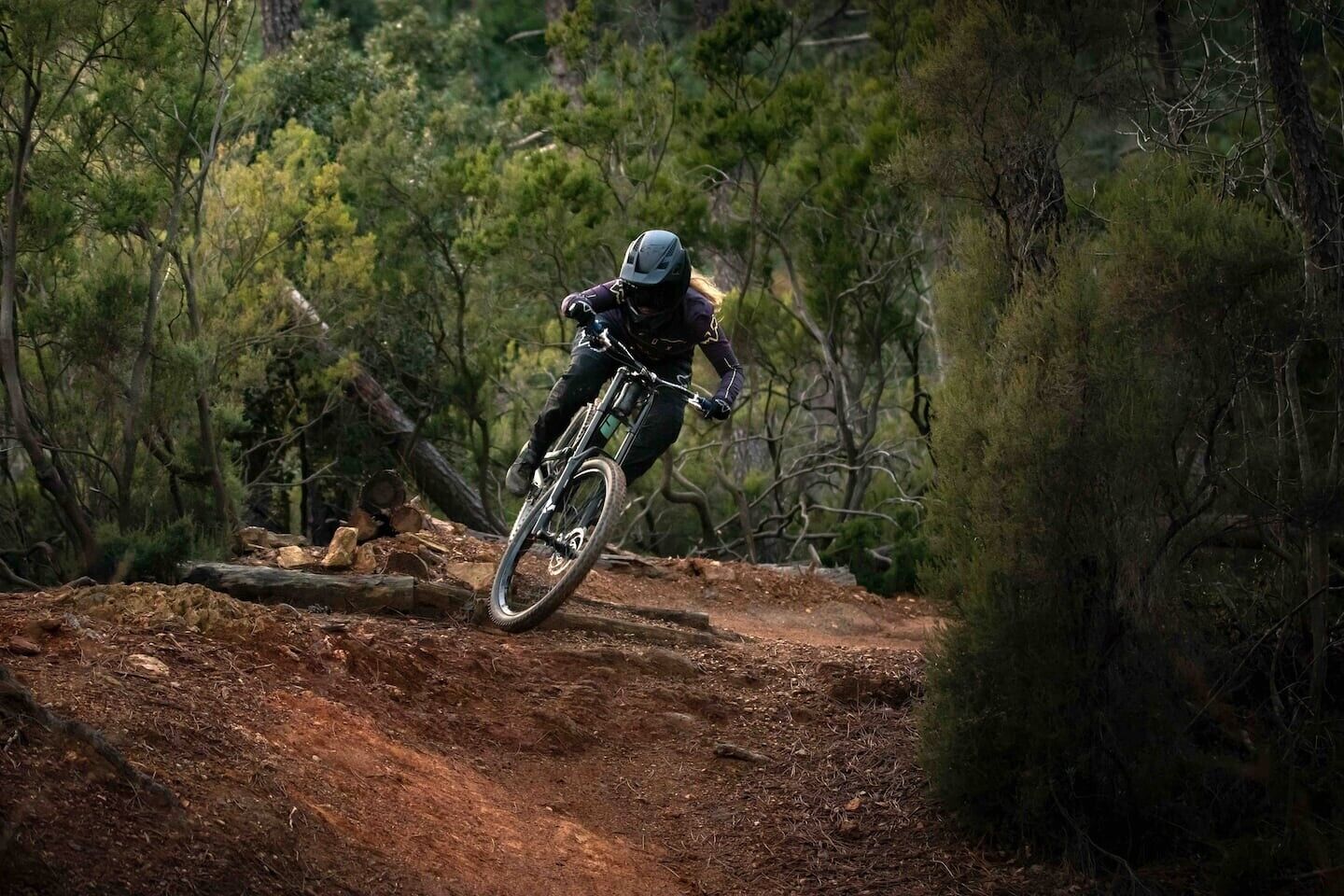 En person cykler på en mountainbike på en jordvej omgivet af træer.