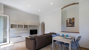 A modern living room with a sofa, TV, dining table, and chairs. - Ca di perti Apartment 1 with Wi-Fi, A/C & Garden (Finale Ligure)