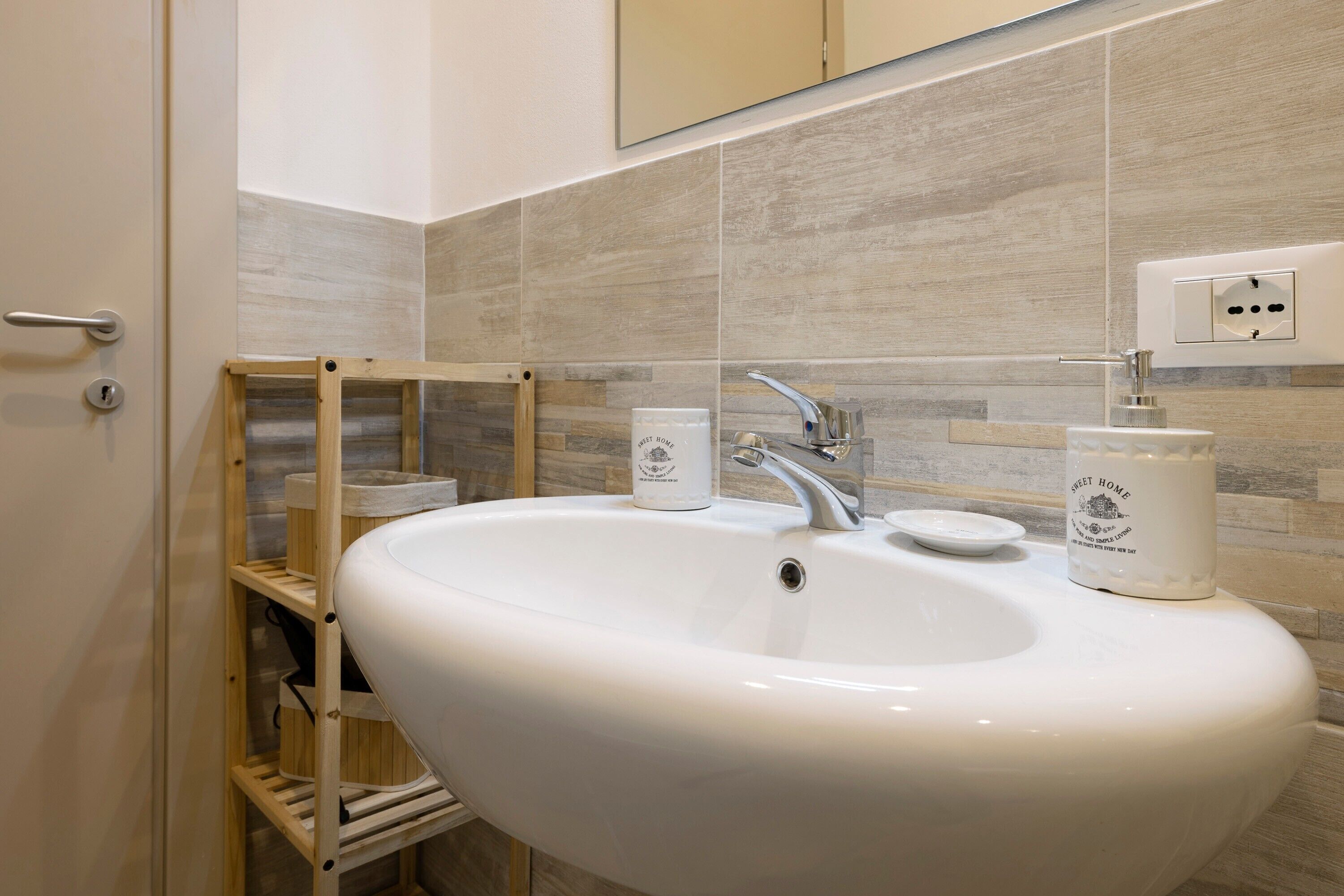 Ein Badezimmer mit einem weißen Waschbecken, einer Holzablage und zwei Seifenspendern.