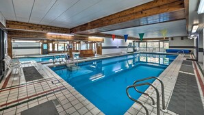 Ein Hallenbad mit Holzbalken, deutlichen Fahrbahnen und einem Rettungsschwimmerstuhl.