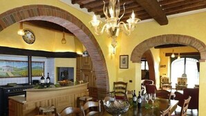 A spacious dining area with a long wooden table, surrounded by chairs, and a chandelier above. - Tuscan Family Villa with Sauna (Bucine)