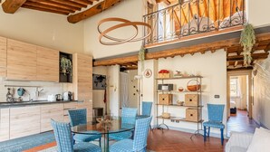 A modern kitchen with wooden cabinets, a glass dining table, and blue chairs.