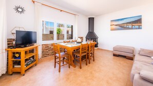 Un salon comprenant un téléviseur, une table à manger en bois avec des chaises, un canapé, une cheminée et un tableau accroché au mur.