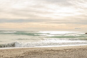 A beach with waves and a cloudy sky.