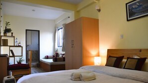 A hotel room with a bed, a wardrobe, a desk, and a chair. - Tanani Newa Home (FishTail) (Lalitpur)