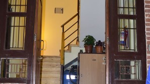 A wooden door with glass panels, a staircase leading to a room, and a brick wall. - Tanani Newa Home (FishTail) (Lalitpur)