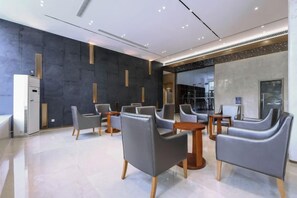 A modern hotel lobby with leather chairs, a reception desk, and a large mirror. - Chongqing Shengshi Jia hua Hotel (Jiangjin Shuangfu Branch) (Chongqing)