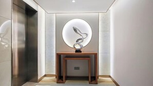 Een moderne hal met een houten console tafel en een ronde lamp.