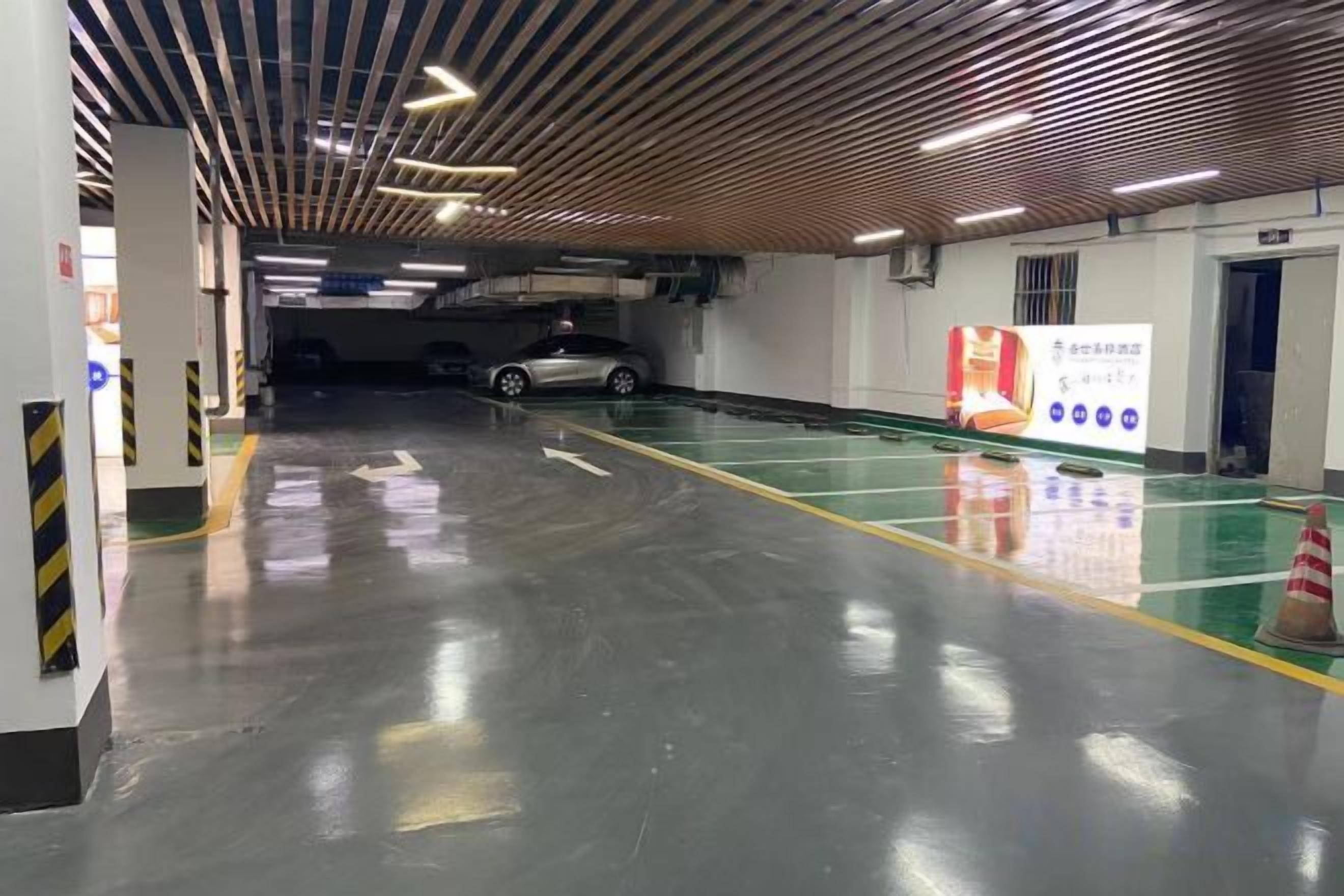 A parking garage with clear directional arrows on the floor, a clean and well-lit environment, and a visible exit door.