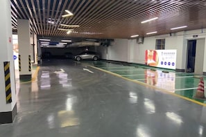 A parking garage with clear directional arrows on the floor, a clean and well-lit environment, and a visible exit door. - Chongqing Shengshi Jia hua Hotel (Jiangjin Shuangfu Branch) (Chongqing)