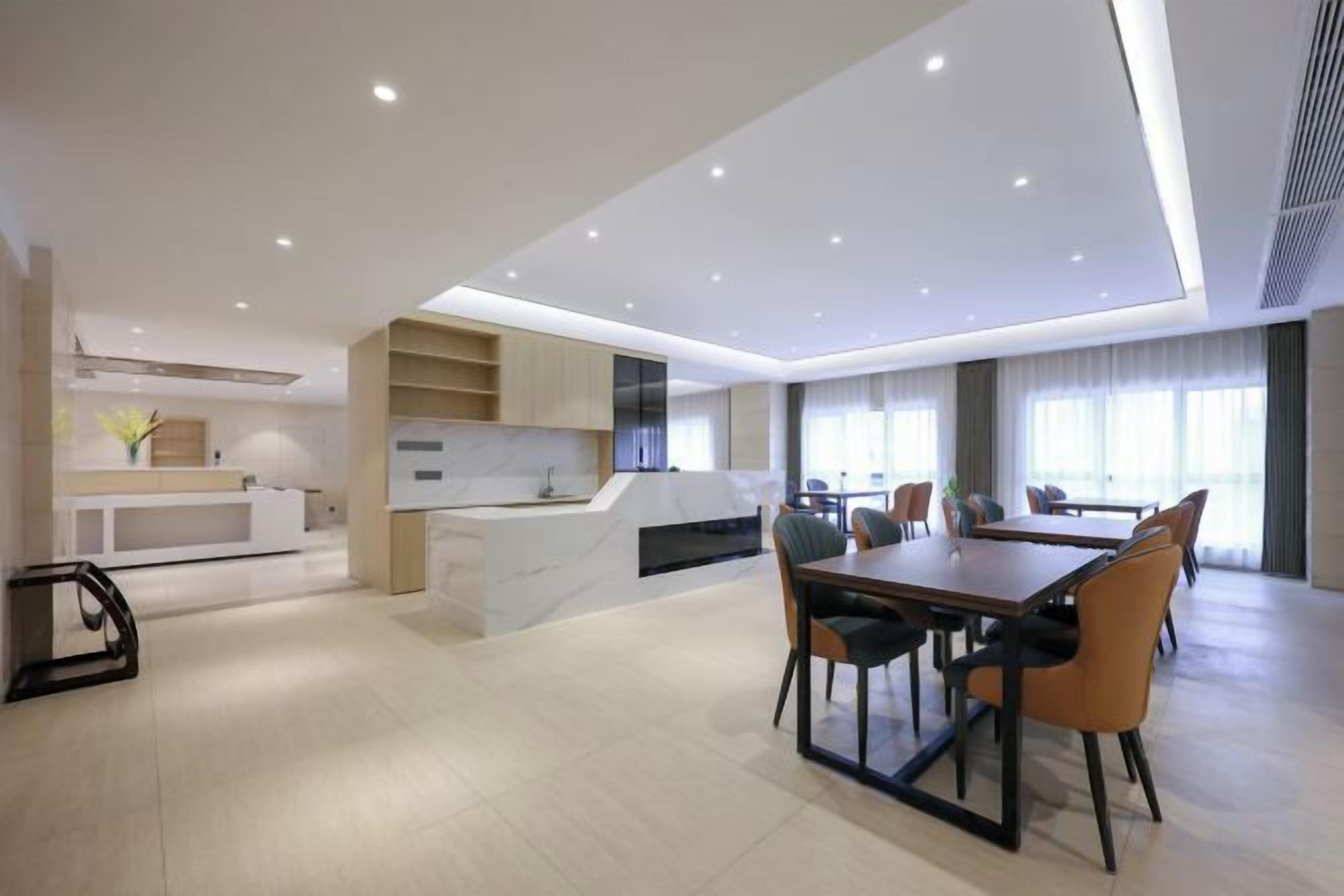 A modern kitchen with a dining area, featuring a large island, built-in appliances, and a seating arrangement with chairs and a table.