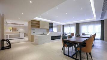 A modern kitchen with a dining area, featuring a large island, built-in appliances, and a seating arrangement with chairs and a table.