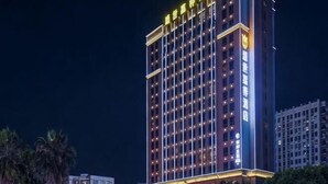 Een hoog hotel met meerdere verdiepingen, verlichte ramen en een opvallende entree.