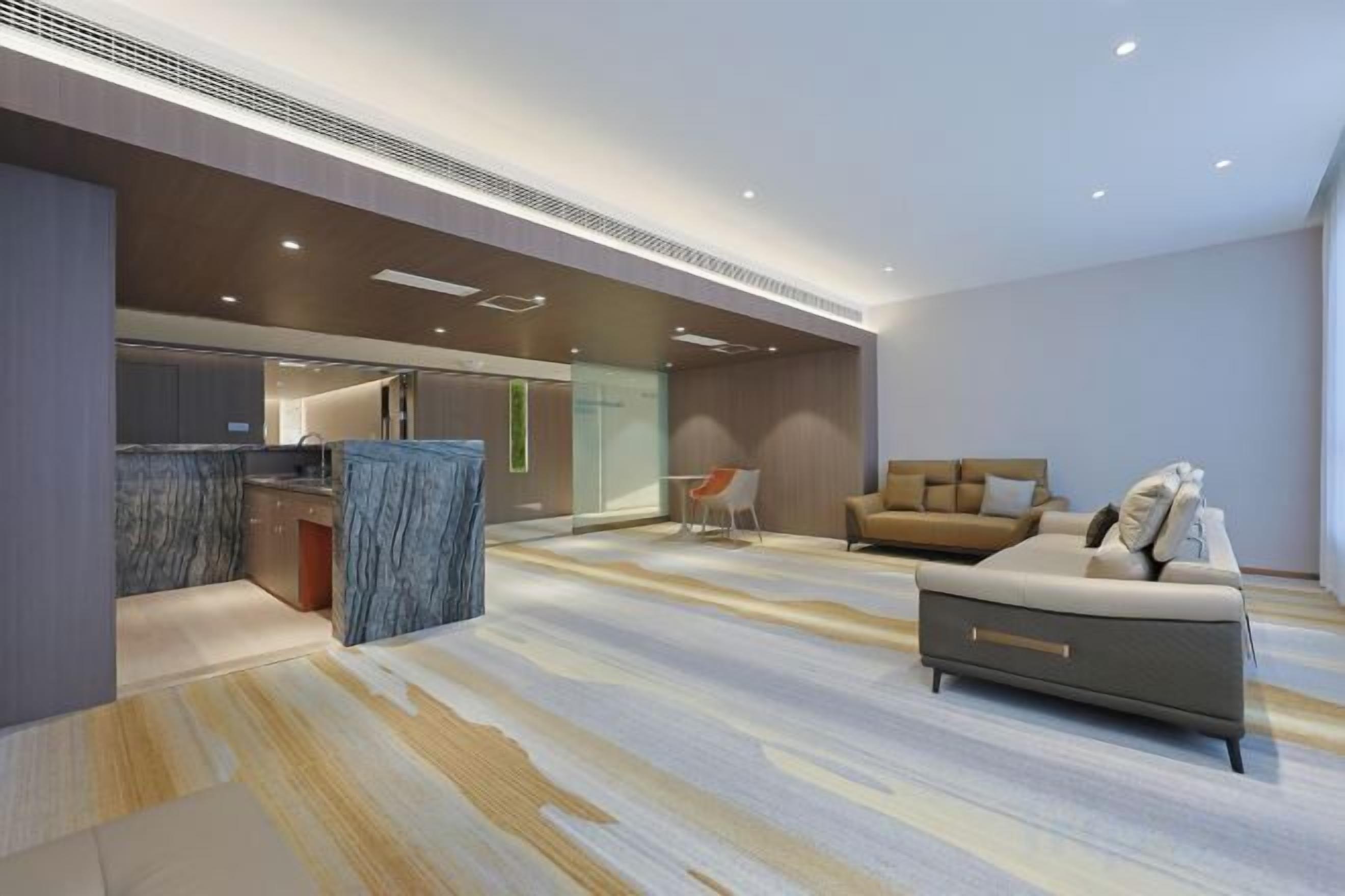 A modern interior with a kitchen, a sofa, and a patterned floor.