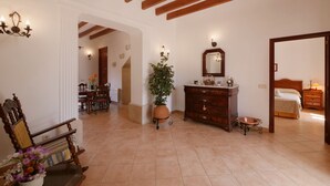 Una habitación amplia con techo de madera, un espejo grande, una cama, un aparador y una zona de comedor con sillas y una mesa.