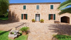 Un edificio de piedra con techo de tejas, persianas verdes y una puerta central.