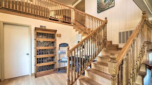 Una escalera de madera con barandilla, una puerta y un aparador con puertas de cristal.