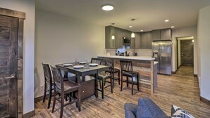 A modern kitchen with a central island, dark wooden chairs, and a built-in microwave. - Newly Built Bigfork Gem ~ 1 Mi to Fish & Hike (Bigfork)