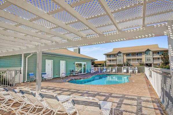 A pool area with lounge chairs and a covered patio.