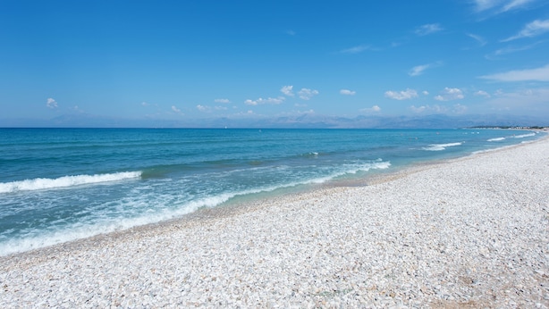 A pebble beach with clear blue water and a clear sky. - Eriva Hotel (Acharavi)