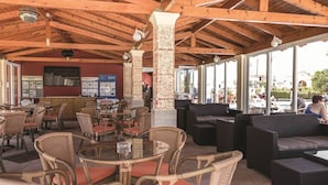 An outdoor café with wicker furniture, a wooden ceiling, and a view of the surrounding area. - Eriva Hotel (Acharavi)