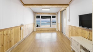 Un couloir aux murs lambrissés, une télévision et une vue sur la plage.