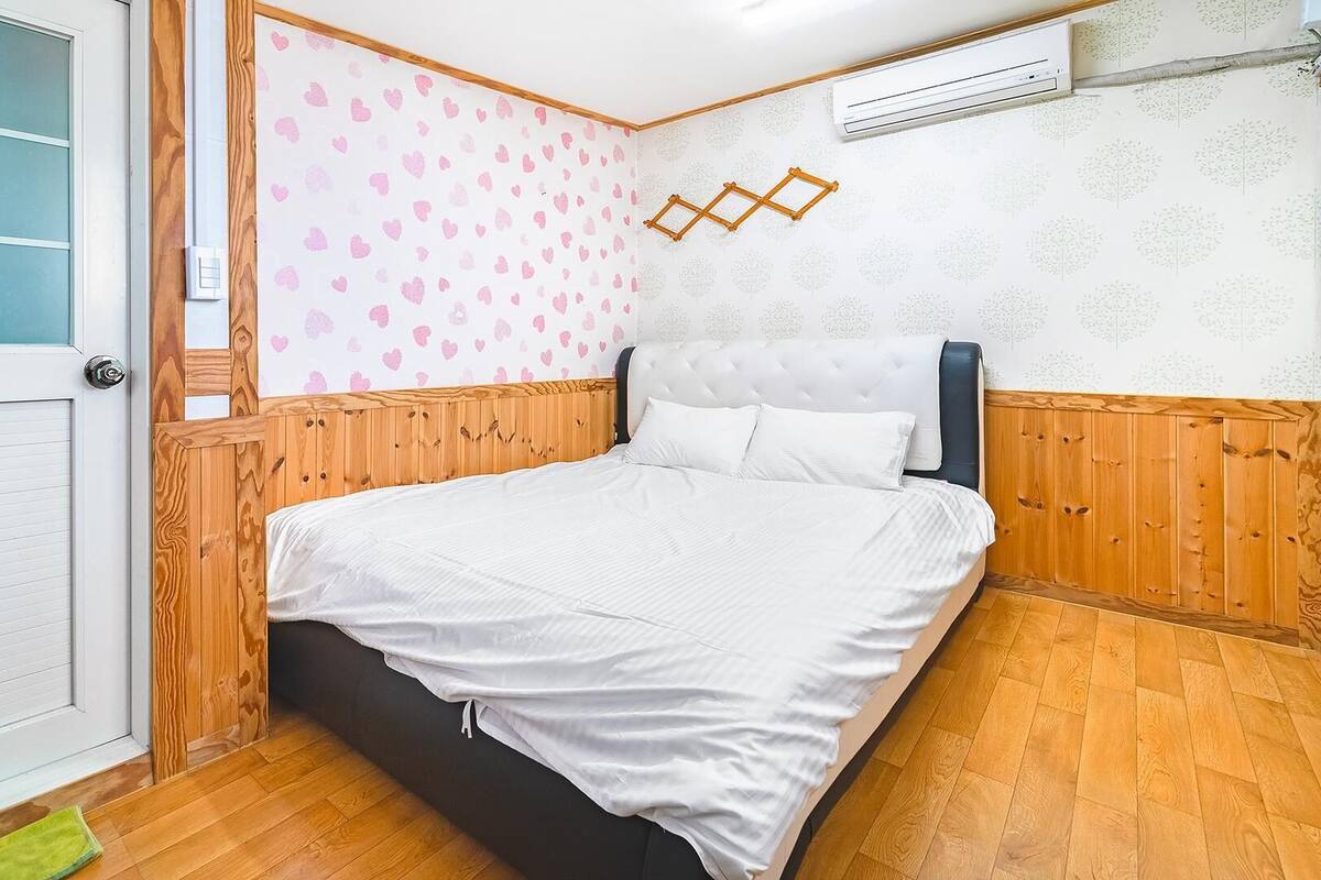 Ein Schlafzimmer mit einem Holzkopfteil, einer weißen Bettdecke und einer Wand mit Muster.