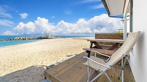 Une vue sur la plage avec une terrasse en bois, une table et deux chaises longues.