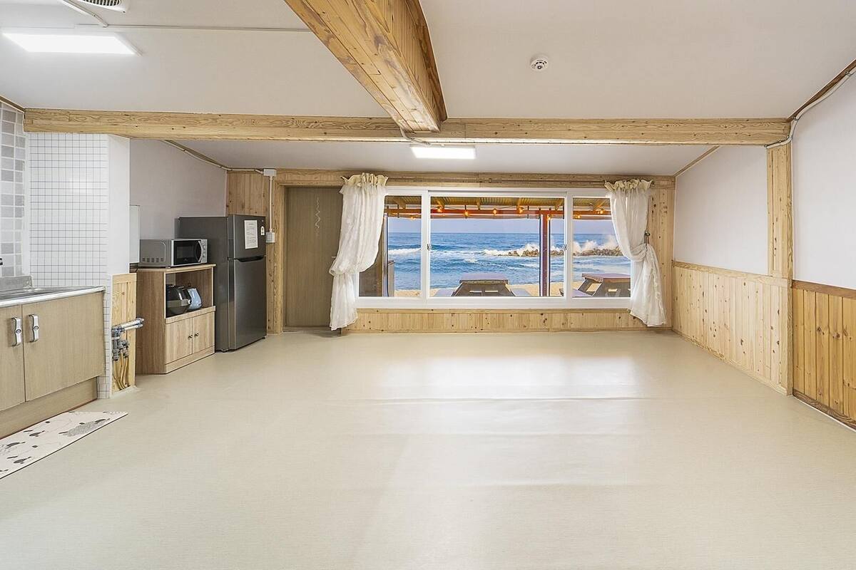 Ein Zimmer mit Meerblick, Holzwänden, einer Küchenzeile und einer Decke mit freiliegenden Balken.