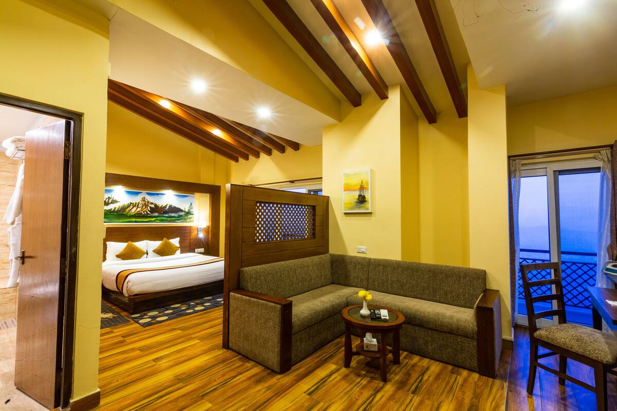 Une chambre d’hôtel avec un lit, un canapé, une petite table et une chaise. Il y a une fenêtre donnant sur l’extérieur.