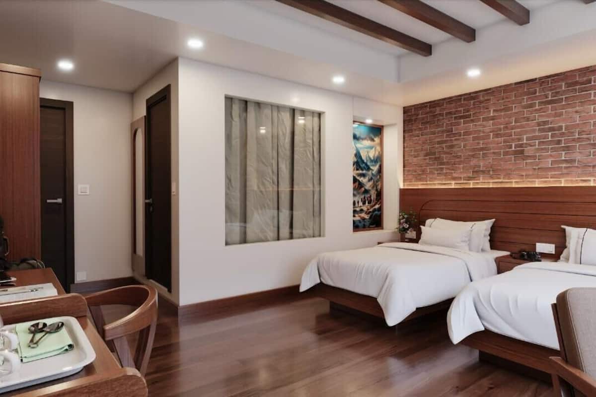 Une chambre d’hôtel avec deux lits, une armoire en bois, un bureau avec une chaise et une grande fenêtre avec des rideaux.