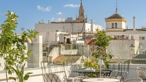 Zona de piscina en la azotea con mobiliario exterior y vista a un edificio histórico al fondo.