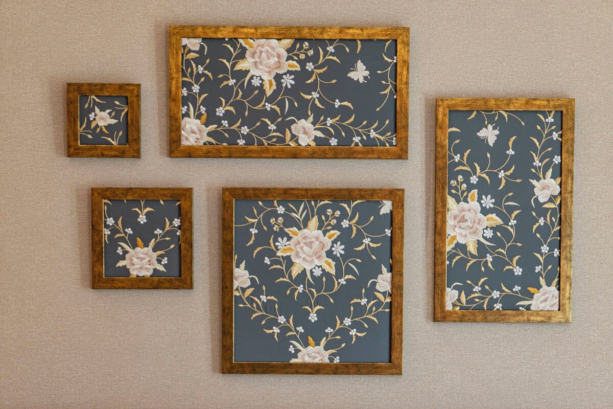 A hotel room with a red headboard, a bed with white bedding, and four framed floral artworks on the wall.