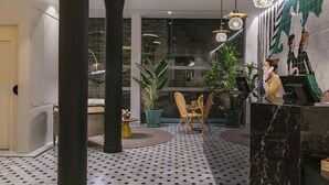 Un vestíbulo moderno con mostrador de recepción, un pilar grande y una zona de estar con sillas y una mesa.