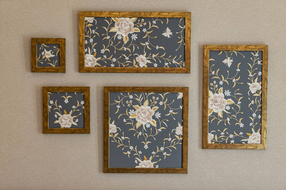 A hotel room with a red headboard, a bed with white bedding, and four framed floral artworks on the wall.