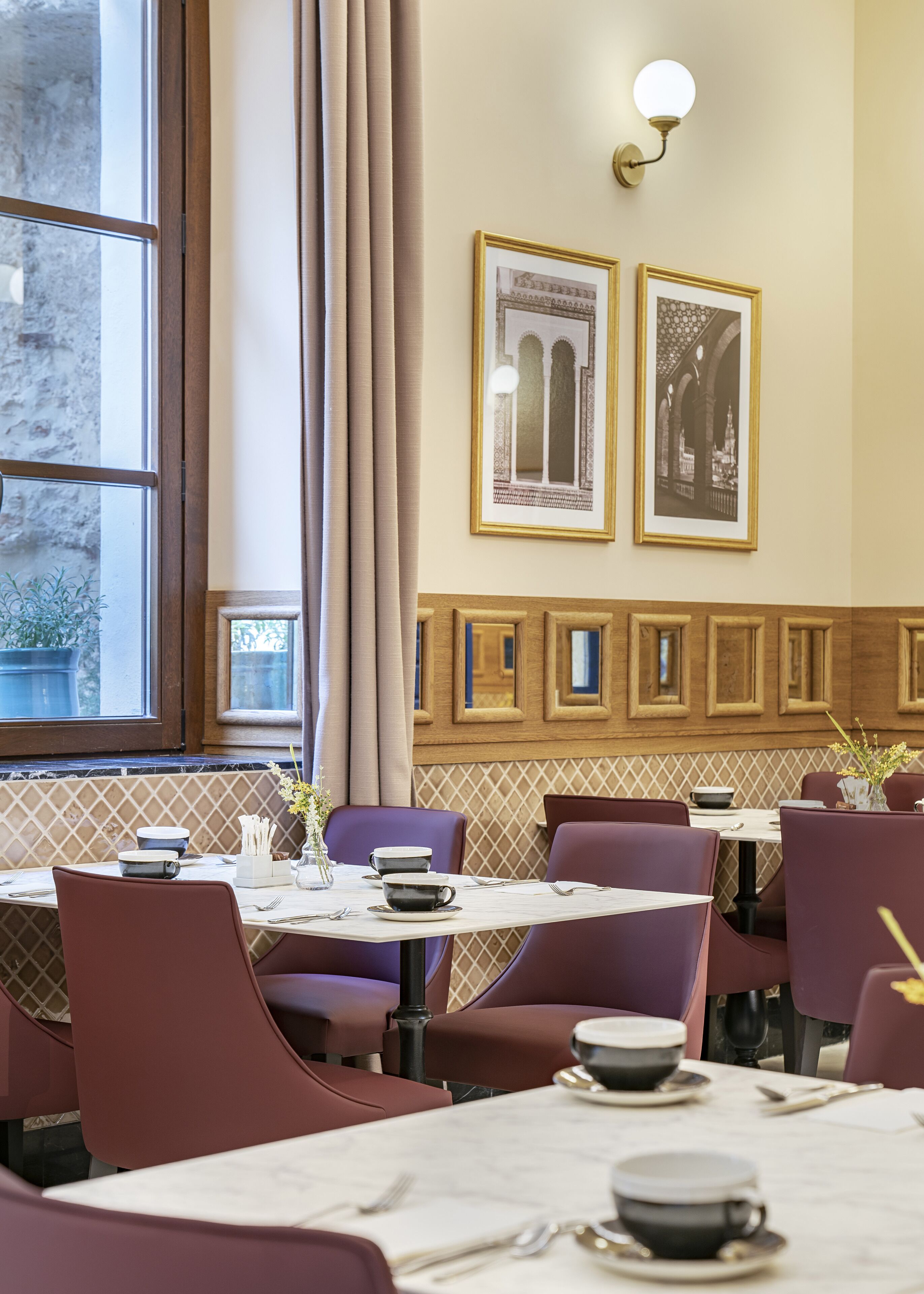 Un restaurant avec des tables surmontées de plateaux en marbre, des chaises violettes et des tableaux encadrés accrochés aux murs.