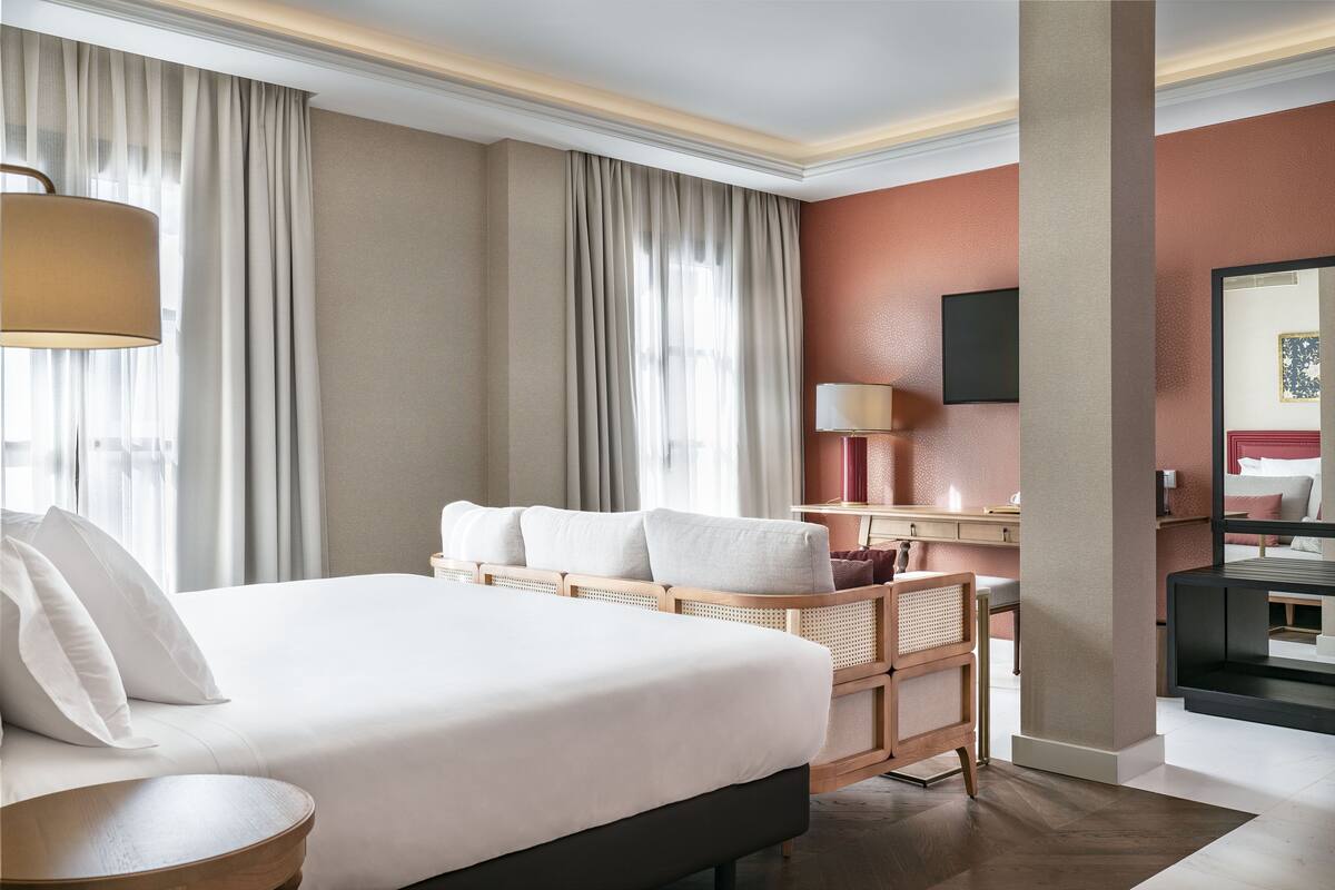 A hotel room with a large bed, a desk, a chair, and a television.