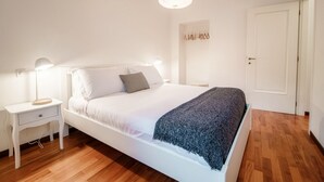 Ett sovrum med en säng, ett sängbord, en lampa och en hängande taklampa.