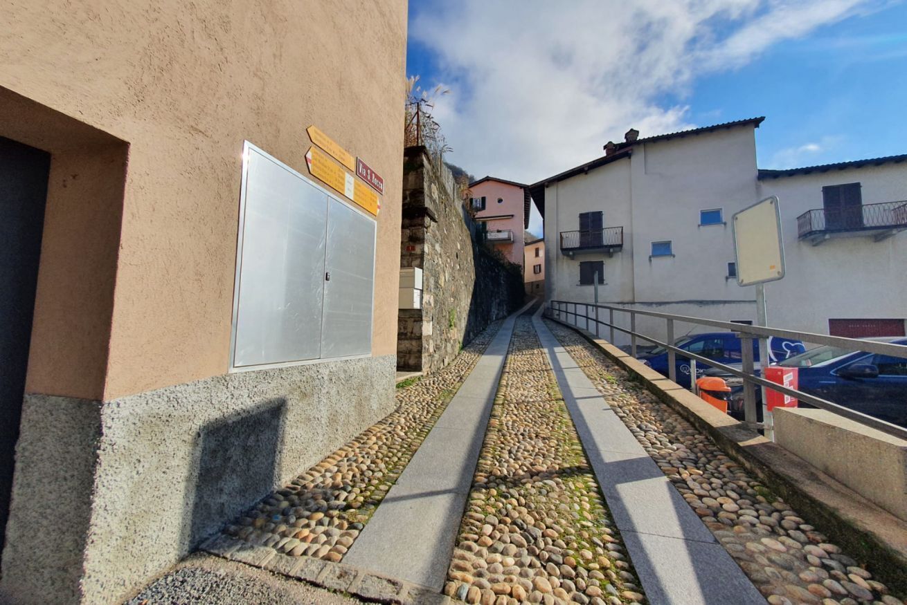 Una calle estrecha con pavimento de adoquines, edificios a ambos lados y un cielo despejado.