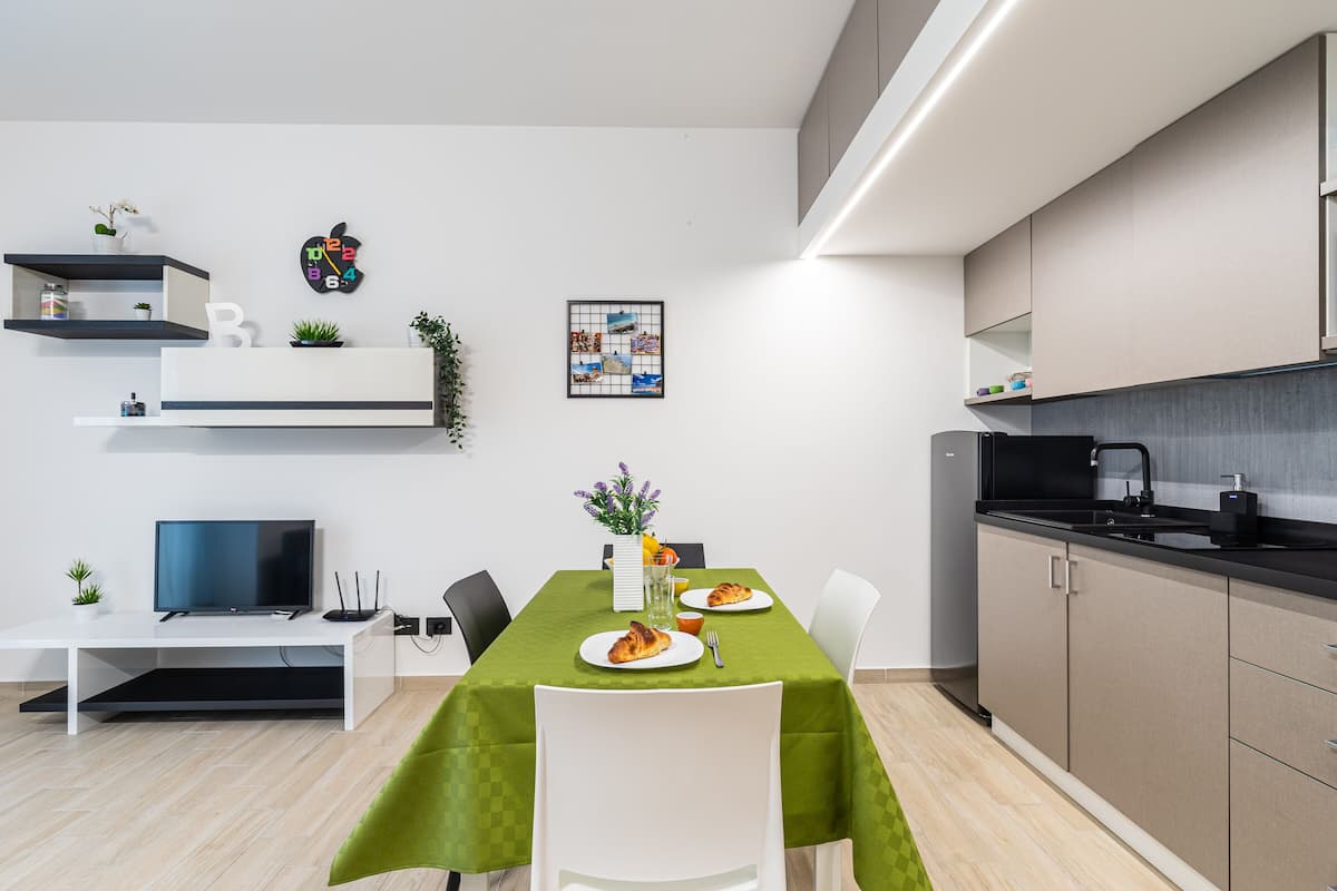 A modern kitchen with a dining table, chairs, and a TV.