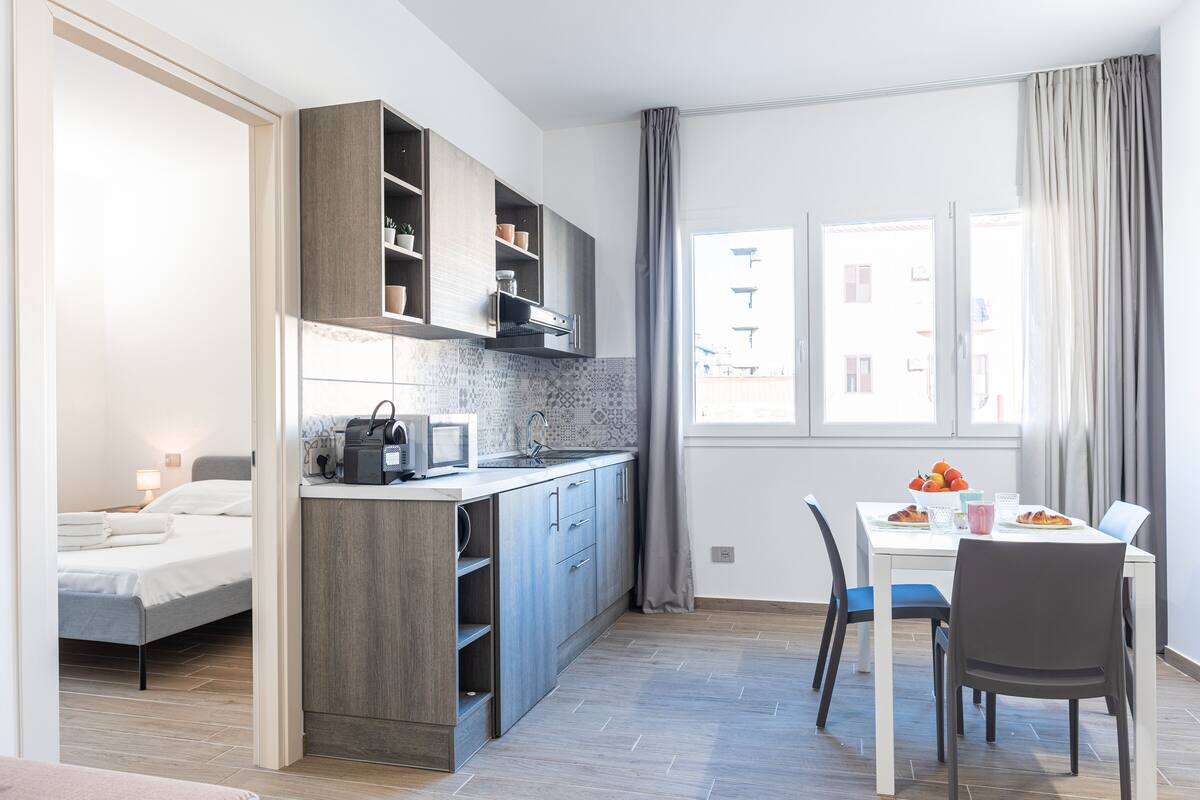A compact apartment with a kitchenette, a dining area, and a bed.